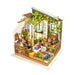 A detailed miniature diorama of an indoor garden scene, perfect for DIY green yard miniature house enthusiasts. It includes a small greenhouse with a variety of tiny plants, flowers, and gardening tools. Furniture includes a white bathtub filled with a pillow, shelves with jars, and a ladder with pots. The walls are adorned with climbing ivy—an ideal relaxing hobby and the best gift for flower lovers. Introducing Miller's Garden DIY Miniature House Kit by Rolife!