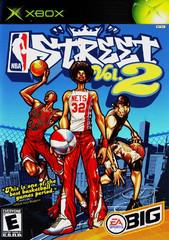 Cover of "NBA Street Vol. 2" by EA Sports, features three dynamic street basketball players, with the central figure wearing a "32" Nets jersey. Set against a city skyline and chain-link fence backdrop, it includes Xbox and EA logos.