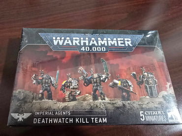 The Games Workshop box set "IMPERIAL AGENTS: DEATHWATCH KILL TEAM" features five customizable Deathwatch Veterans miniatures against a dark red background on a wooden surface. The intricate models are displayed in armor with weapons, labeled as "5 Citadel Miniatures.