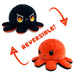 A TeeTurtle Reversible Red and Fire Eyes Octopus Plushie by Teeturtle is shown in two different moods. The black octopus has an angry expression with red and yellow flames in its eyes. When flipped inside out, the orange octopus displays a slightly grumpy expression. Two red arrows and the word "REVERSIBLE!" highlight this mood plush toy feature.
