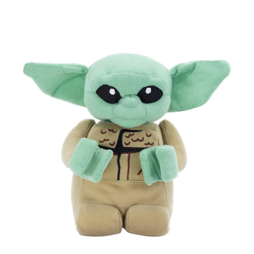 A plush toy resembling Baby Yoda from "The Mandalorian." Large, black eyes, a small nose and mouth, and oversized green ears give it a charming look. The tan robe has a detailed design on the front. This delightful plushie stands upright against a plain white background, perfect for any LEGO Star Wars fan. Introducing the LEGO Star Wars: The Child Plush Minifigure by Little Shop of Magic!