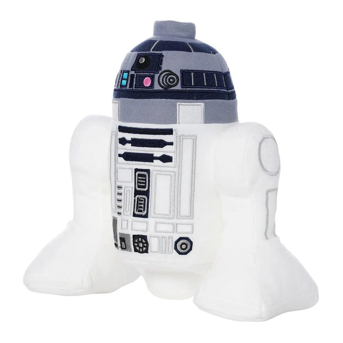 A plush toy depicting a character resembling R2-D2, a popular droid from the Star Wars franchise. The LEGO Star Wars: R2-D2 Plush Minifigure by Little Shop of Magic is predominantly white with gray and blue accents, featuring familiar detailed patterns, buttons, and lights on its cylindrical body and dome-shaped head to mimic the original character's design. Ideal for imaginative play or as a companion to your LEGO Star Wars collection.