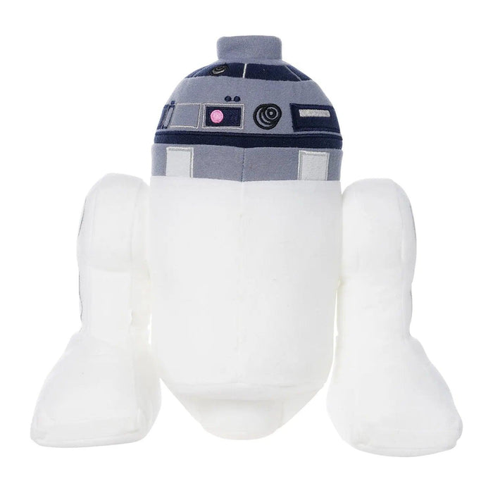 A stuffed toy designed to look like a character from Star Wars, this Little Shop of Magic LEGO Star Wars: R2-D2 Plush Minifigure is primarily white with a cylindrical body and dome-shaped head, featuring blue, grey, and black detailing with lens-like features. It has uncharacteristic plush arms and legs, perfect for imaginative play.