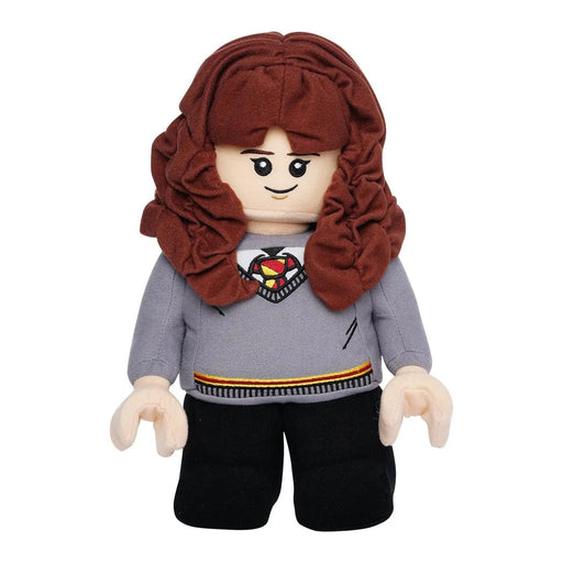 A plush toy resembling *Little Shop of Magic's LEGO Harry Potter: Hermione Granger Plush Minifigure*, with long brown hair, a happy face, and wearing a gray sweater adorned with the red and yellow Hogwarts crest over a white collared shirt. The toy also wears black pants and has jointed, blocky arms and legs typical of LEGO figures.