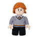 A Little Shop of Magic LEGO Harry Potter: Ron Weasley Plush Minifigure depicts a character with orange hair, freckles, and a smiling face. Wearing a grey sweater with a red and yellow striped tie underneath, black pants, and black shoes, this Harry Potter figure has a friendly and approachable appearance with soft, rounded features.