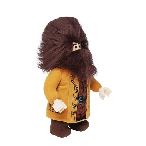 A plush character with a large brown beard and hair, reminiscent of Little Shop of Magic LEGO Harry Potter: Hagrid Plush Minifigure, dons a long yellow coat over a brown outfit. The toy features stitched facial details and limbs, giving it a whimsical and charming appearance.