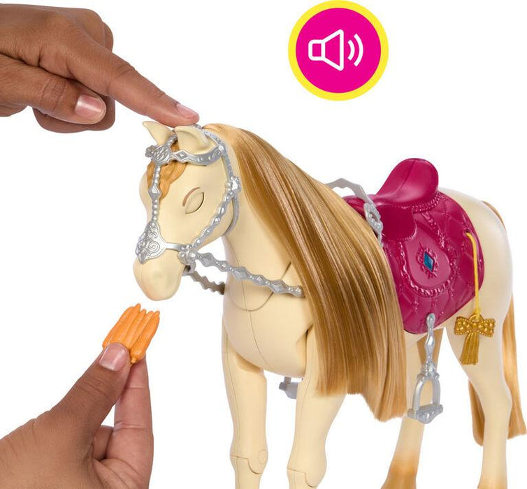 A person interacts with a Mattel Barbie Mysteries: The Great Horse Chase Interactive Toy Horse that has a flowing blonde mane and a pink saddle with a decorative emblem. The person is holding a small carrot in one hand, aiming it toward the horse's mouth, while the other hand touches the horse’s forehead. A sound icon is present above the Mattel Barbie Mysteries: The Great Horse Chase Interactive Toy Horse.