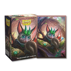 A box and card sleeve from Arcane Tinmen's Dragon Shield collection showcases The Bushdrake, a fantasy creature with large eyes, pointed ears, and a green leaf-like crown. Set in a lush forest environment, the creature is depicted holding a round object. This set includes 100 Brushed Art Sleeves ideal for TCG cards.