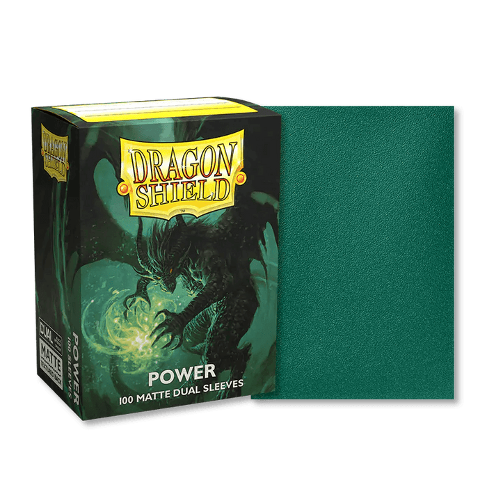 Box of Dragon Shield: Standard 100ct Sleeves - Power (Dual Matte) featuring an illustration of a dark dragon holding a green orb, emitting light, on a fantasy background. Next to the box is one of the green matte card sleeves. The box has vibrant yellow "Dragon Shield" text and other labeling details.
