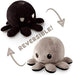 The TikTok-famous Everything Games TeeTurtle Reversible Black and Gray Octopus Plushie is a super soft toy with two moods. One side sports a black, angry face with furrowed eyes, while the other reveals a light gray, happy grin. Arrows and "REVERSIBLE!" text highlight its flipping feature to reflect your mood.