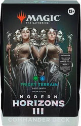 Box of Magic: The Gathering Modern Horizons 3 Commander Deck titled "Tricky Terrain". The artwork shows two female figures in elaborate armor holding staffs, surrounded by spectral faces. Tagline: "Grow Value". Aged 13+. Includes collector booster sample pack, plus 2 legendary traditional foils.