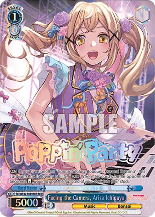 A colorful, anime-style trading card features a cheerful, blonde girl with twin-tails, wearing a vibrant stage outfit with a blue and purple blazer adorned with bows and frills over a white blouse. She stands amidst a burst of colorful confetti. Part of the BanG Dream! Girls Band Party! Countdown Collection by Bushiroad, the card reads "Facing the Camera, Arisa Ichigaya (BD/WE42-E089BDR BDR) [BanG Dream! Girls Band Party! Countdown Collection]" at the bottom.
