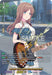 A trading card features a young woman with long brown hair, wearing an off-the-shoulder blue and white dress. She's playing a red electric guitar, reminiscent of the BanG Dream! series. The card's text includes her abilities, strengths, and unique actions in a game. The card's name is "As Her True Self, Soyo Nagasaki (EXS) (DZ-BT01/EXS09EN) [Fated Clash]" by Bushiroad.
