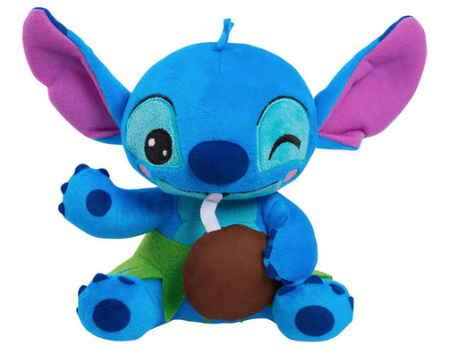 A Disney Stitch Feed Me Small Plush from Disney, this plush features a predominantly blue character with large pink ears, winking with its right eye. Dressed in green shorts and holding a brown coconut with a white straw, this delightful beanbag plush captures the charm of Stitch perfectly.