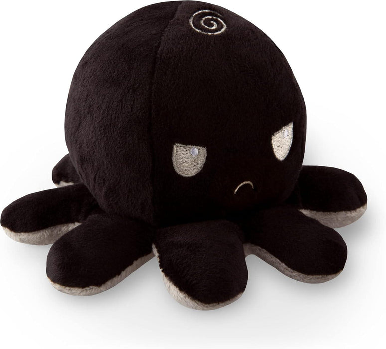 A TeeTurtle Reversible Black and Gray Octopus Plushie by Everything Games with a round head, eight short legs, and a small spiral on top. The reversible octopus plushie has an angry expression with downturned eyes and a frowning mouth. The underside of the legs is a light gray color. This TikTok sensation looks incredibly soft and cuddly.
