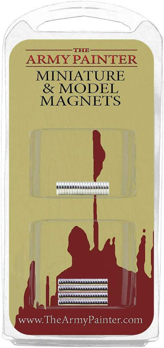 A packaging of "The Army Painter Miniature and Model Magnets." The top half of the package displays two neat rows of small, silver magnets in clear plastic compartments. Perfect for changing weapons, the magnets come in multiple sizes. The background is beige with red paint splatters and the brand name "Army Painter" at the top. The bottom has a website link.