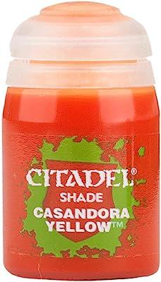 The Citadel Shade - Casandora Yellow is ideal for matte shading on miniatures. It has a transparent lid, an orange bottle with a green splatter pattern, and the iconic white Citadel logo, allowing you to see the paint inside.