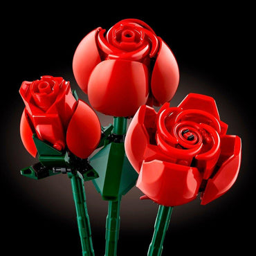 Three red roses from the LEGO Icons Bouquet of Roses are presented against a dark background. Crafted to mimic natural blooms, the central rose is fully open, surrounded by two in partial bloom.