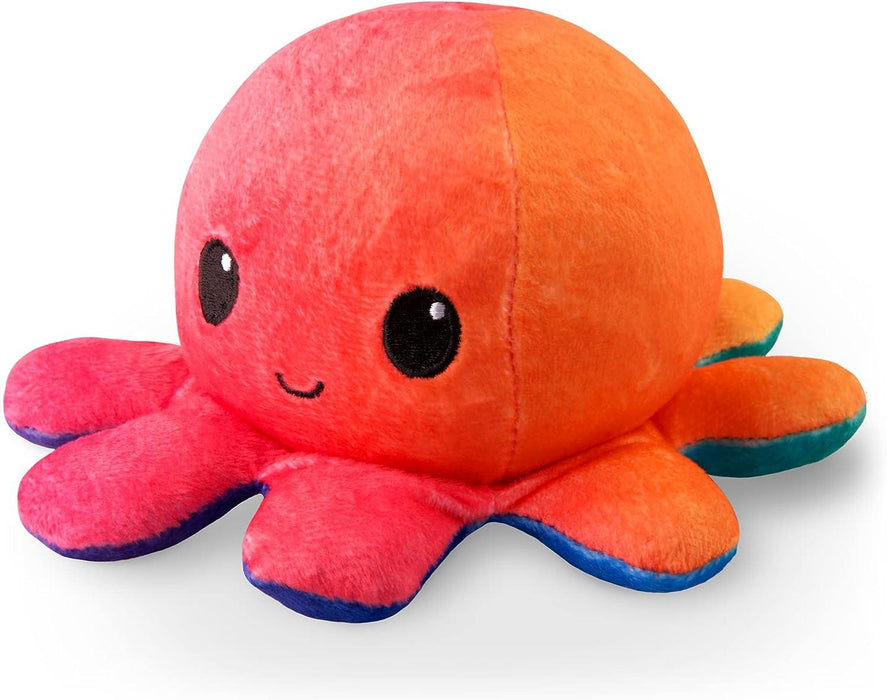 A round, plush toy shaped like an octopus, this TeeTurtle Reversible Sunset and Mermaid Octopus Plushie by Everything Games features a vibrant gradient of red to orange with a light blue edge along its legs. Large, black embroidered eyes and a small, smiling mouth give it a cute and cheerful appearance—making it the perfect gift.