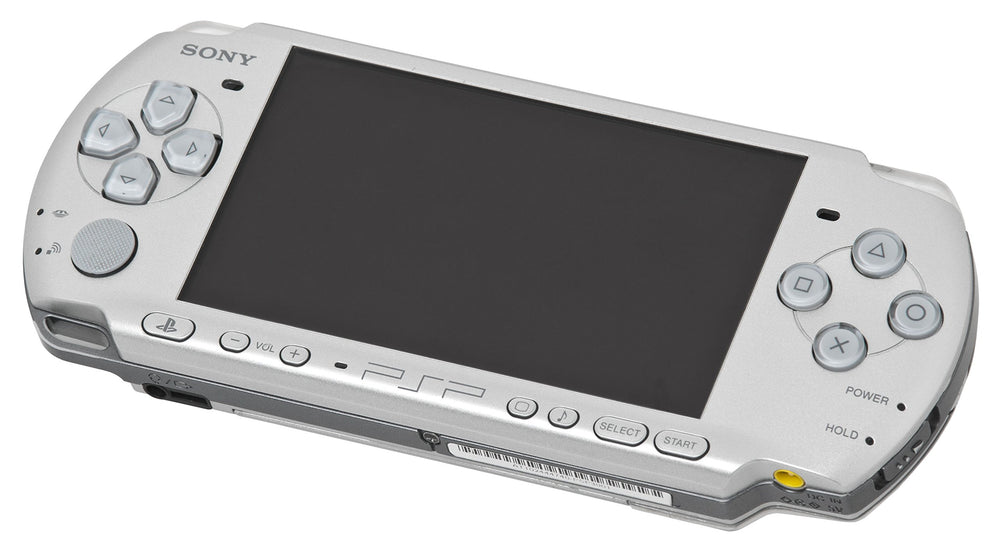 A silver Playstation Portable handheld console by Sony is depicted from a slightly elevated perspective. This compact gaming device showcases a large screen, with a directional pad on the left side, buttons on the right, and multimedia controls below, including "Volume" and "Home," with the Sony brand prominently displayed.