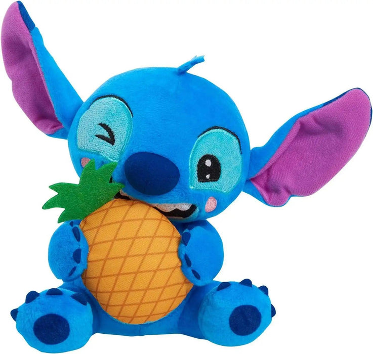 This Disney Stitch Feed Me Small Plush depicts Stitch, the blue alien with large ears from Disney's "Lilo & Stitch," holding a plush pineapple. With a playful expression and a wink, this Disney Stitch Feed Me Small Plush toy is brightly colored with a blue body, purple inner ears, and detailed stitching.