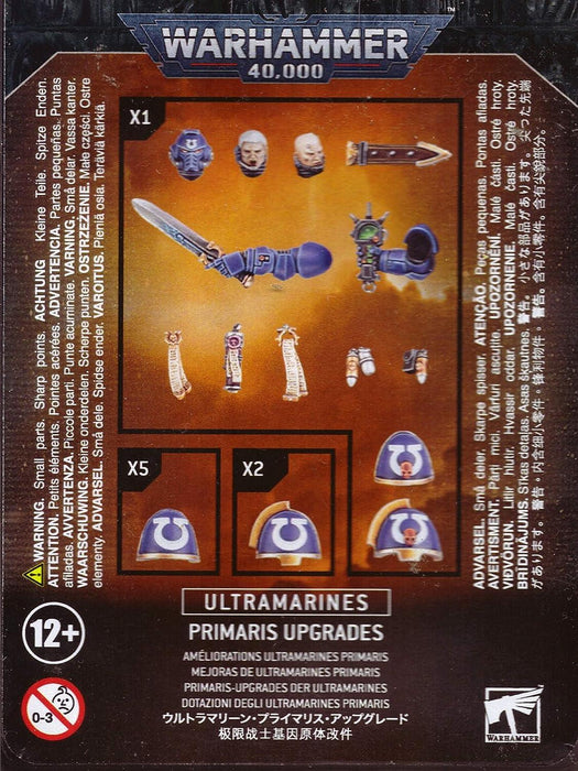 The image shows the packaging for "ULTRAMARINES: PRIMARIS UPGRADES" by Games Workshop. It includes various components for customization: a sword with a hand, a plasma pistol with a hand, power armour shoulder pads with Ultramarines insignia, a head with a laurel wreath, and a helmet. Suitable for ages 12+.