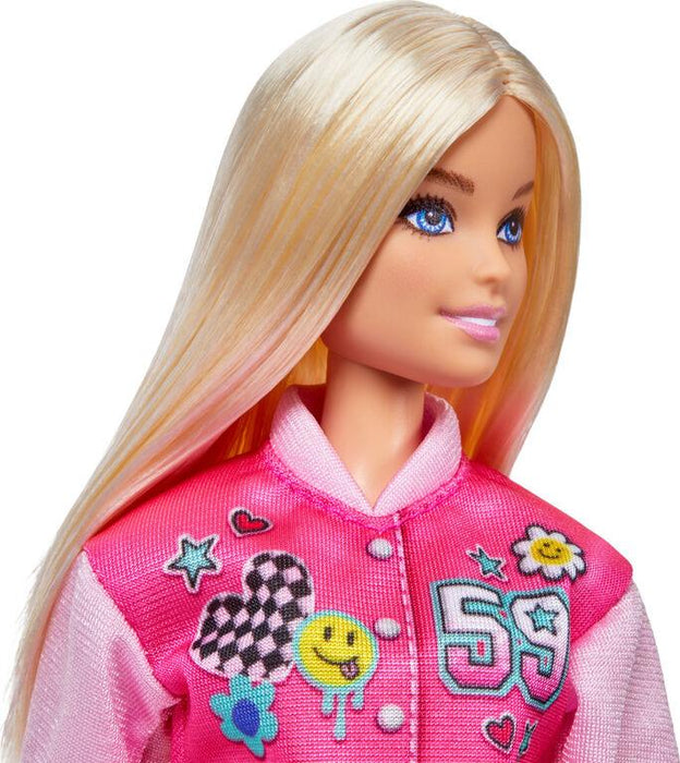 A Barbie-I Love School-Blonde Doll with long, straight blonde hair and bright blue eyes is dressed in a vibrant pink jacket adorned with colorful patches, including a heart, smiley face, flower, and the number 59. Perfect for the Mattel playset, this doll has a pleasant expression and is photographed against a white background.