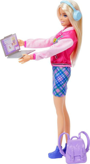A blonde doll with long hair stands holding a laptop. She wears a pink and white jacket with colorful designs, plaid shorts, and blue sneakers. Light blue headphones rest on her head. A purple backpack is placed on the ground next to her. This Mattel Barbie-I Love School-Blonde Doll captures the excitement of back to school perfectly.