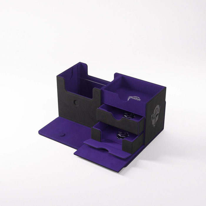 A black and purple multi-compartment storage box, perfect for multifunctional card storage, is displayed against a plain white background. The box features several open compartments of varying sizes and an innovative fold-out section at the bottom. A hand icon is visible on the side of the box. The product name is THE ACADEMIC 133+ XL TOLARIAN EDITION - BLACK & PURPLE by Game Genic.