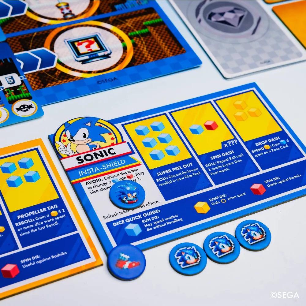 The Sonic the Hedgehog: Sonic Roll board game by Kessler Corporation features Chaos Emeralds, a special ability Sonic character card, colorful tokens, and Zones Cards. Its vibrant design uses blue and yellow with iconic Sonic graphics. ©SEGA is included.