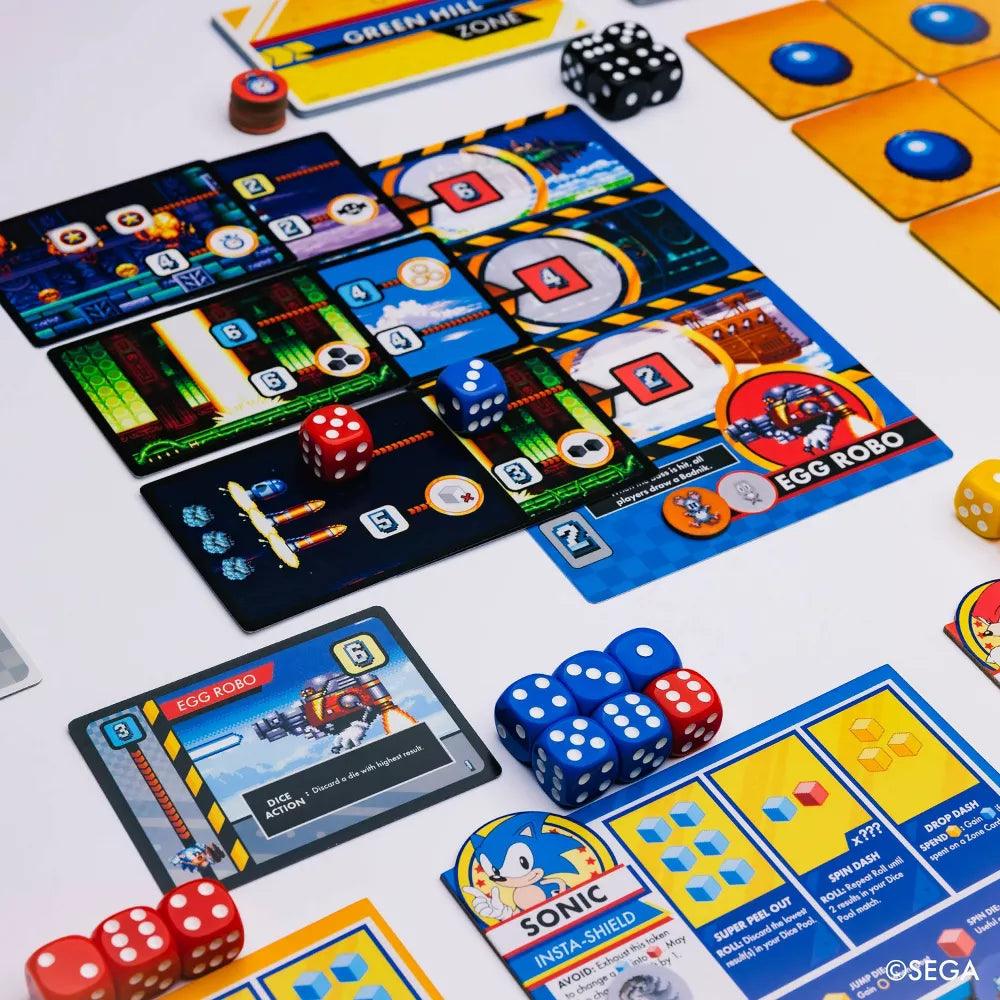 Experience Sonic the Hedgehog: Sonic Roll by Kessler Corporation with vibrant elements including character cards, blue and red dice, and "Egg Robo" and "Sonic" boards. Dive into the adventure with Zones Cards featuring Chaos Emeralds. The ©SEGA logo is at the bottom right corner.