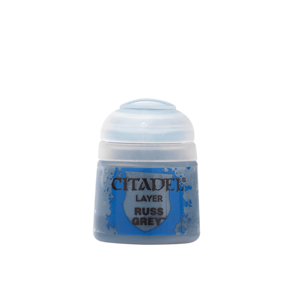 The Citadel Layer - Russ Grey by Citadel is a small, clear plastic paint pot with a rounded lid and blue label. Containing blue-grey paint, it's perfect for edge highlighting miniatures. Blue paint splatters embellish the text against a solid grey background.