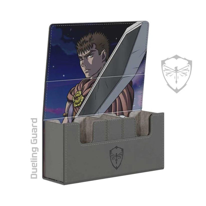 A Dueling Guard The Struggler Deck Box is open, revealing the interior lid adorned with an anime-style character holding a large sword. The case, made of vegan leather, is gray with a logo of a stylized shield featuring an insect in the center. "Dueling Guard" is written vertically on the left side of the image.