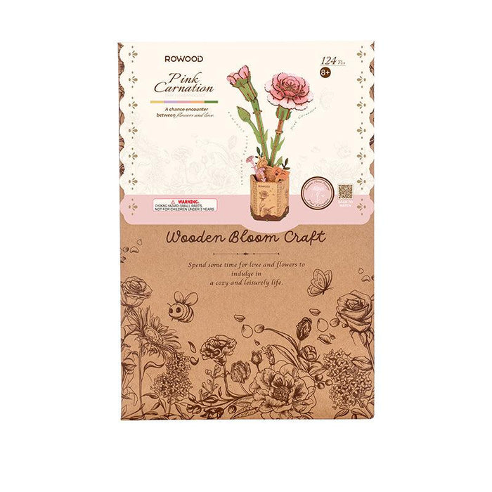 Front packaging of Rolife's Rowood Pink Carnation Craft kit. The top section displays an illustration of a pink carnation in a mason jar, with branding above. The bottom section showcases detailed floral sketches in brown. The kit is for 12+ years, featuring 124 pieces.