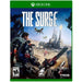 Cover art for the Xbox One game "The Surge" by Focus Home Interactive. It shows a protagonist in an exo-suit with a weapon, facing a futuristic industrial facility under attack. Two flying drones are visible in the background. Featuring an innovative limb-targeting system, this action-RPG's logo is at the top, with ratings and developer logos at the bottom.