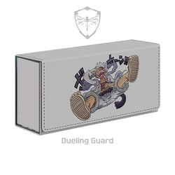 Introducing the SUN GOD EMBROIDERED DECK BOX from Dueling Guard. This rectangular storage box features a grey exterior with a striking animated character in a dynamic, likely screaming, pose accompanied by stylized text in the background. Crafted from vegan leather and boasting stitching along the edges, it showcases the Dueling Guard branding with a shield containing a butterfly above the name.