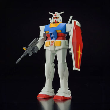 The Best Mecha Collection 1/144 RX-78-2 Gundam (Revival Ver.) by Bandai stands out against a black background with a white body, red feet, and red and blue highlights. It holds a gun in its right hand and a red shield with a yellow star in its left, featuring a blue chest and remarkable head design.