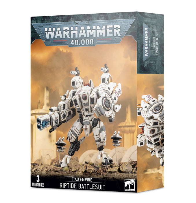 Box art of T'AU EMPIRE: RIPTIDE BATTLESUIT. The box features a detailed white XV104 Riptide with heavy burst cannon and drones, standing in a war-torn futuristic landscape. The top prominently displays the Warhammer 40,000 logo. The bottom left mentions "3 miniatures" in the set. Produced by Games Workshop.
