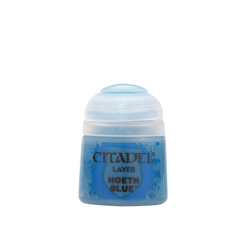 The image features a small, round, clear plastic pot labeled "Citadel Layer - Hoeth Blue" with a white flip-top lid filled with blue paint. This product by Citadel is ideal for edge highlighting miniatures, and blue splatters decorate the label against a gray background.