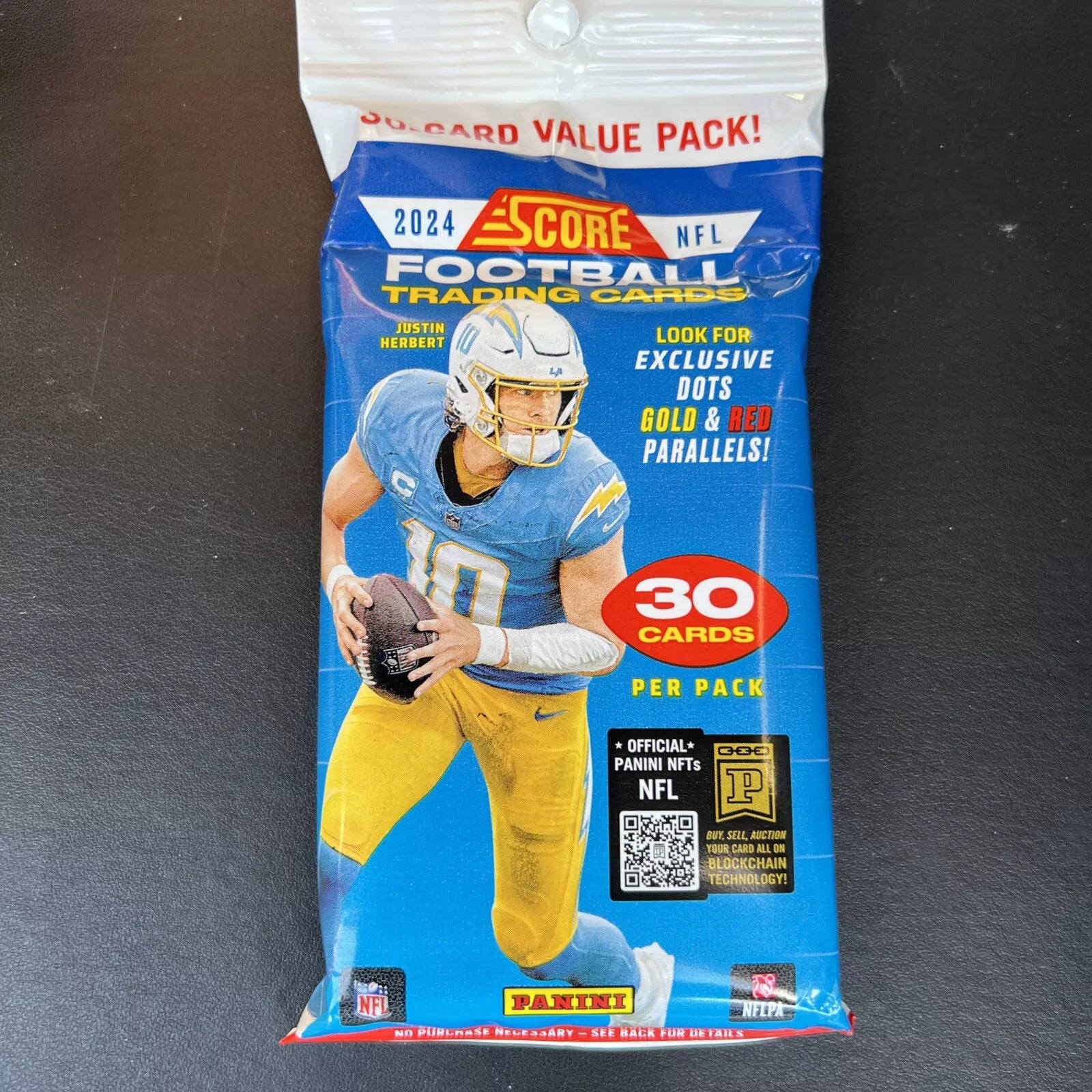 The Panini NFL 2024 Score Football Single Pack Trading Cards contain 30 cards and feature a player in a light blue and yellow uniform holding a football on the package. The pack highlights 