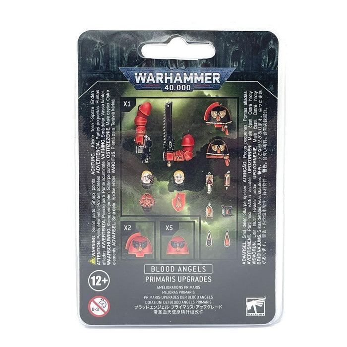 The image showcases the back of a Games Workshop BLOOD ANGELS: PRIMARIS UPGRADES miniature set packaging. It features images of plastic components such as shoulder pads, helmets, a weapon, and symbols for customizing Primaris Space Marines. The predominantly black package is accented with white and red text and logos.
