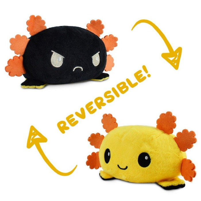 A Teeturtle TeeTurtle Reversible Black and Yellow Axolotl Plushie is shown in two versions. The top version is black with orange appendages and an angry expression. An arrow points to the word "REVERSIBLE!" and then to the bottom version, which is yellow with orange appendages and a happy expression. Perfect for TikTok trendsetters!