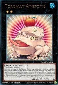 A Yu-Gi-Oh! trading card titled "Toadally Awesome [MAGO-EN134] Rare" features an illustration of two toads stacked on top of each other. The top toad balances an apple on its head. This 1st Edition Maximum Gold Xyz/Effect Monster boasts ATK 2200 and DEF 0, against a vibrant starburst background.