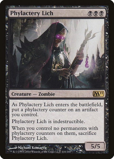 A rare "Magic: The Gathering" card titled "Phylactery Lich" from the Magic 2011 set features a Creature Zombie that wields a glowing purple staff topped with a skull. Its abilities include placing a phylactery counter on an artifact you control, making Phylactery Lich indestructible as long as the artifact remains intact. It has power and toughness ratings of 5/5.