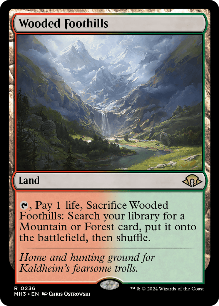 The Wooded Foothills [Modern Horizons 3] Magic: The Gathering card, part of Modern Horizons 3, depicts a lush mountain scene from Kaldheim with a valley filled with green foliage, trees, and shrubs under a bright, cloudy sky. Card text reads: 