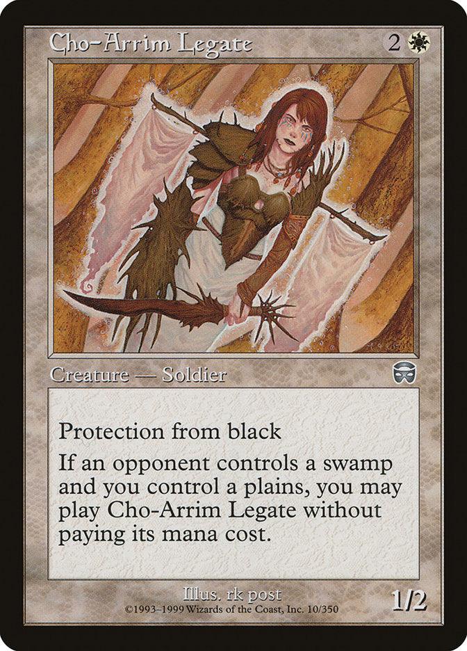 A "Magic: The Gathering" card titled Cho-Arrim Legate [Mercadian Masques], from the Mercadian Masques set, depicts a brown-haired female soldier with wings, clad in armor, and holding a staff. This creature card costs 2 white mana and has 1 power and 2 toughness. It features Protection from black and an ability to play for free when conditions are met. Art by