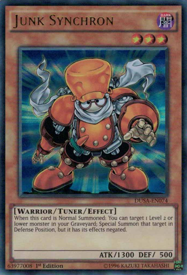 The image shows the Yu-Gi-Oh! Junk Synchron [DUSA-EN074] Ultra Rare card, depicting a humanoid with an orange helmet, blue outfit, and cape. This Tuner/Effect Monster has 1300 ATK and 500 DEF, featuring Special Summon abilities in its card text.