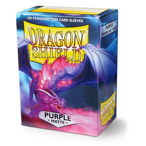 A box of Dragon Shield: Standard 100ct Sleeves - Purple (Matte) from Arcane Tinmen is displayed. The box features a detailed illustration of a purple dragon with glowing red eyes, large wings, and a fierce expression. The text reads "Dragon Shield" at the top and "Purple Matte" at the bottom. The box contains 100 durable card sleeves in standard size.