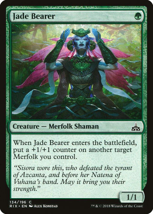 The image is a Magic: The Gathering card titled "Jade Bearer [Rivals of Ixalan]" from the brand Magic: The Gathering. It features artwork of a green-skinned Merfolk Shaman in intricate jade and leaf armor with raised arms. This 1/1 creature adds a +1/+1 counter to another Merfolk in play. The artist is Alex Konstad.