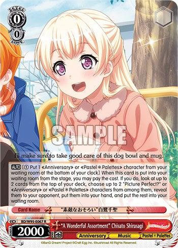 A colorful trading card featuring an anime-style character with blonde hair, purple eyes, and a cheerful expression. She's wearing a pastel outfit and a pink bow. Text at the bottom provides description and game stats, with the card name "A Wonderful Assortment" Chisato Shirasagi [BanG Dream! Girls Band Party! 5th Anniversary]. Part of the Bushiroad BanG Dream! 5th Anniversary set, this rare character card features 2000